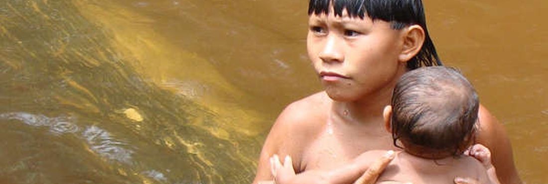 Menino Suruwaha banha bebê em riacho