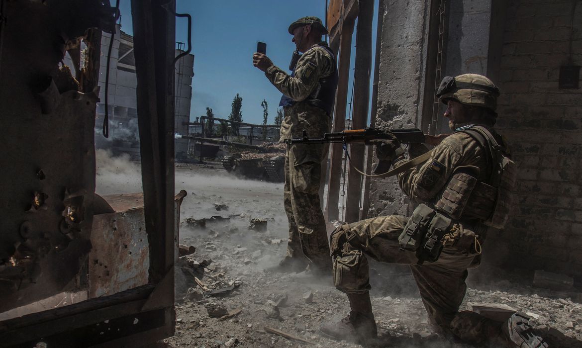 Soldado ucraniano observa enquanto tanque dispara na direção de tropas russas em área industrial da cidade de Sievierodonetsk, na Ucrãnia