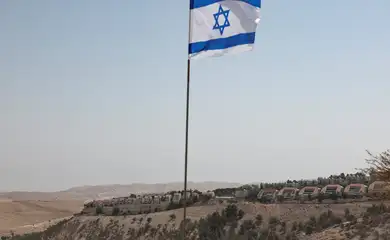 An Israeli flag flutters, as part of the Israeli settlement of Maale Adumim is visible in the background, in the Israeli-occupied West Bank, August 14, 2025. REUTERS/Ronen Zvulun