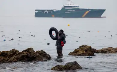 A man holds an inflatable ring, as he stands in the water, with the Spanish Guardia Civil (Civil Guard) in the background, amid mass crossings of migrants on foot and by sea from Morocco into Spanish territory, in Ceuta, Spain, July 31, 2026. REUTERS/Jon Nazca        TPX IMAGES OF THE DAY