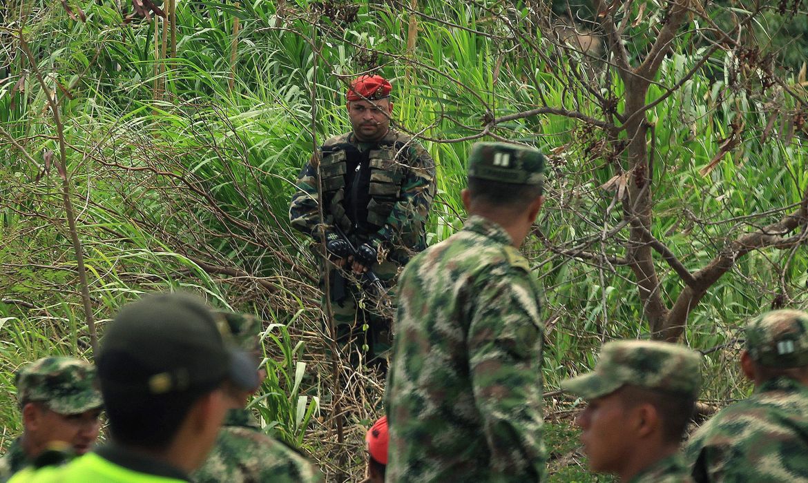 Soldados colombianos são observados por militares venezuelanos, enquanto ajudam colombianos a atravessar a fronteira entre os dois países pelo Rio Tachira 
