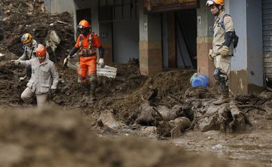 Bombeiros se equilibram sobre a lama acumulada na Rua Teresa, em trabalho de busca nos deslizamentos de terra das chuvas em Petrópolis.