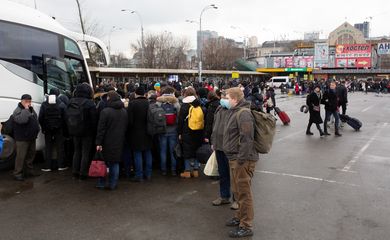 Pessoas se reúnem em uma estação de ônibus enquanto tentam sair de Kiev
