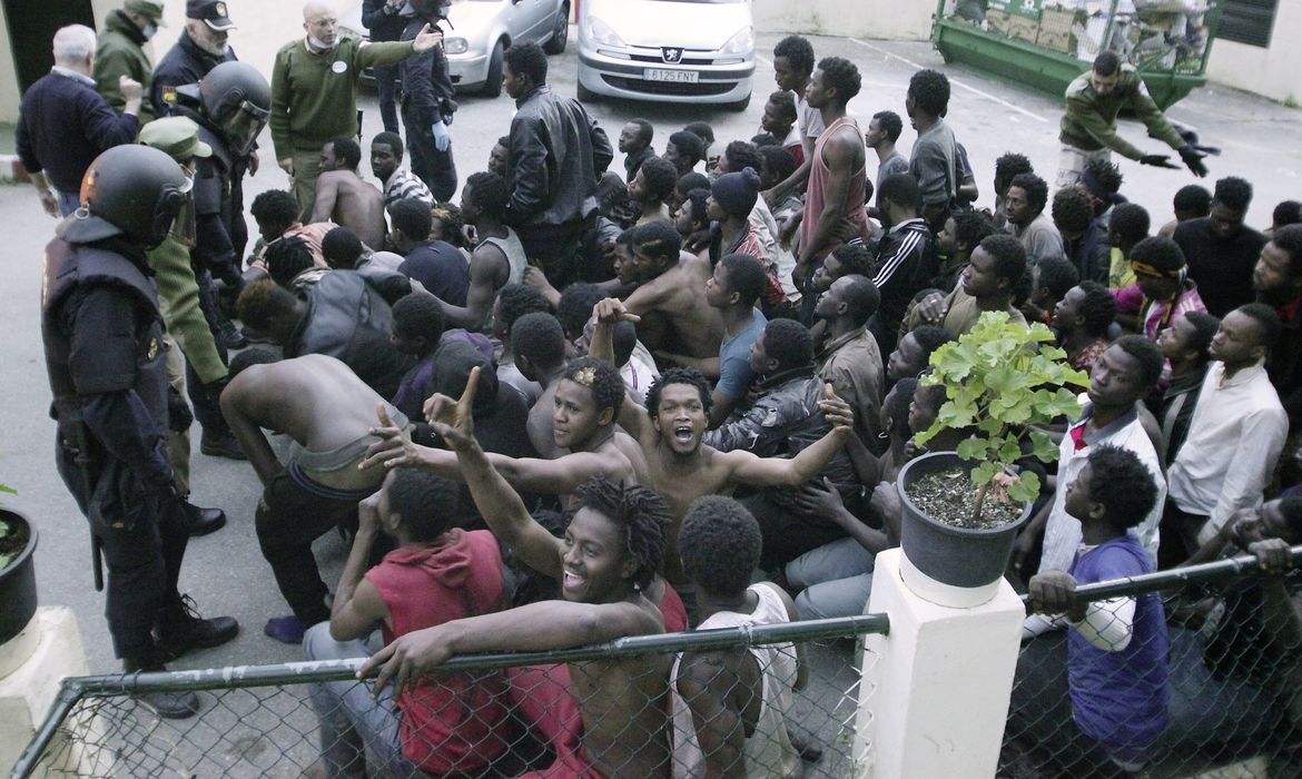 Dezenas de imigrantes subsaarianos celebram após ter conseguido pular a cerca fronteiriça da Espanha em Ceuta, norte da África, no dia 17 de fevereiro último