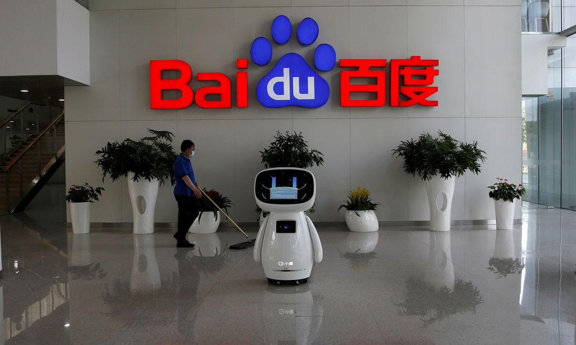 FOTO DE ARQUIVO: Um trabalhador usando uma máscara facial limpa o chão, perto de um robô Baidu AI que mostra uma máscara facial em sua tela, na sede do Baidu em Pequim, após o novo surto de doença coronavírus (COVID-19), China, 18 de maio de