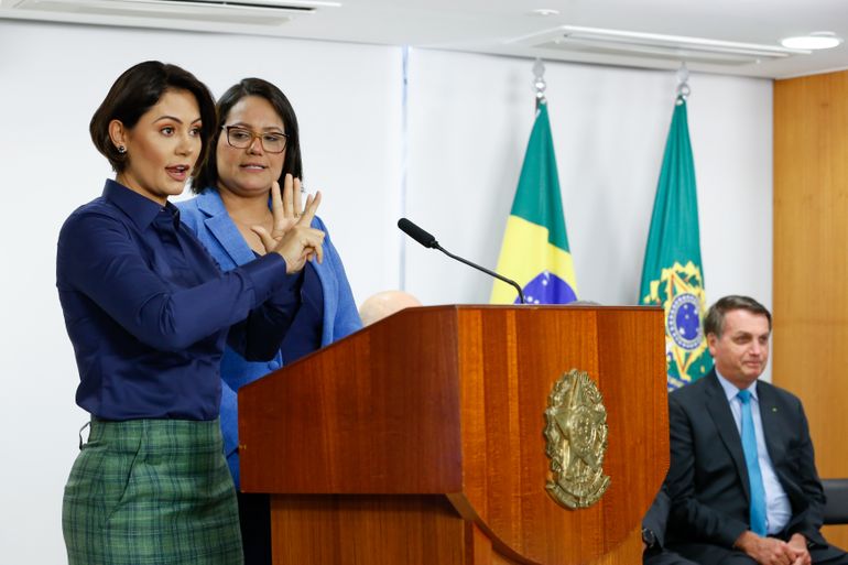 A primeira-dama, Michelle Bolsonaro, faz um pronunciamento na Língua Brasileira de Sinais (Libras), acompanhada de uma intérprete, durante a cerimônia de lançamento da Política Nacional de Educação Especial e Homenagem ao Mês dos Surdos