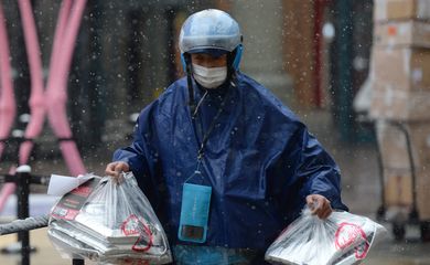 Ele.me deliveryman wearing a face mask delivers food amid snowfall on Valentine's Day in Beijing