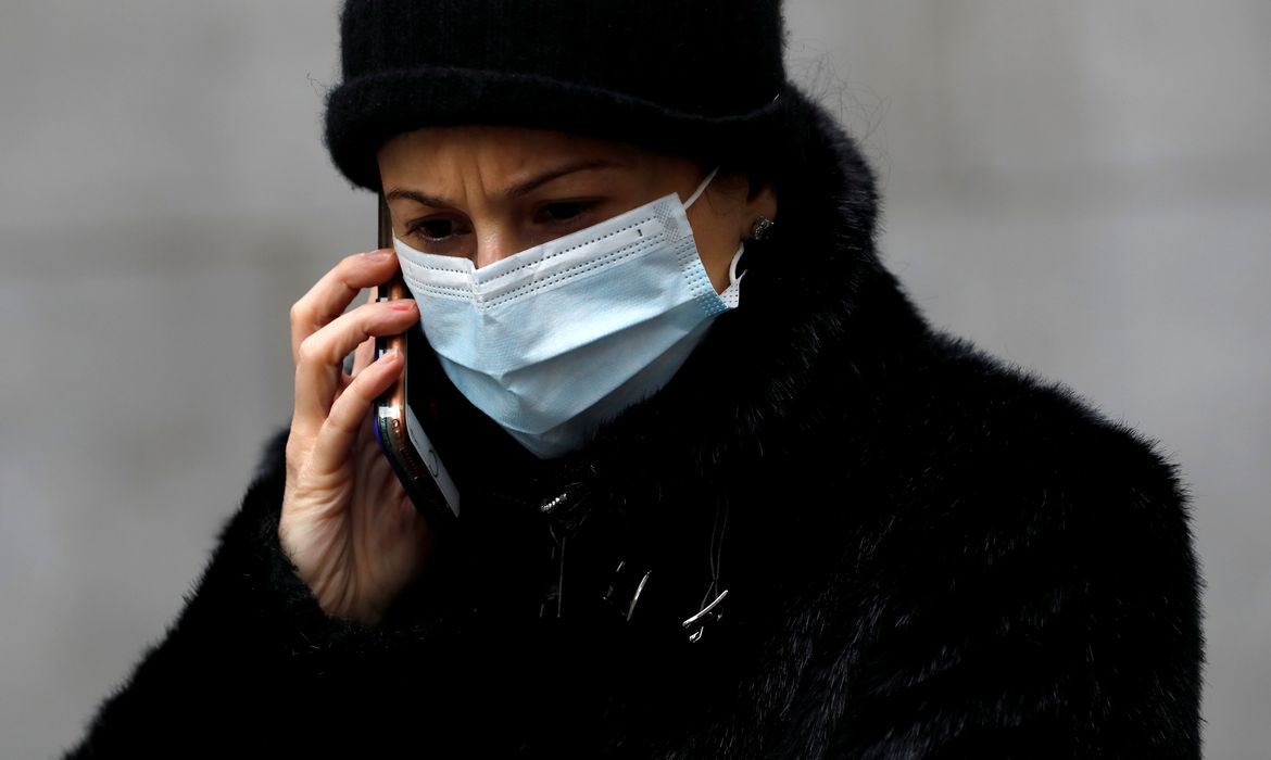 FILE PHOTO: A woman in a surgical mask uses her cellphone after more cases of coronavirus were confirmed in Manhattan, New York City, New York