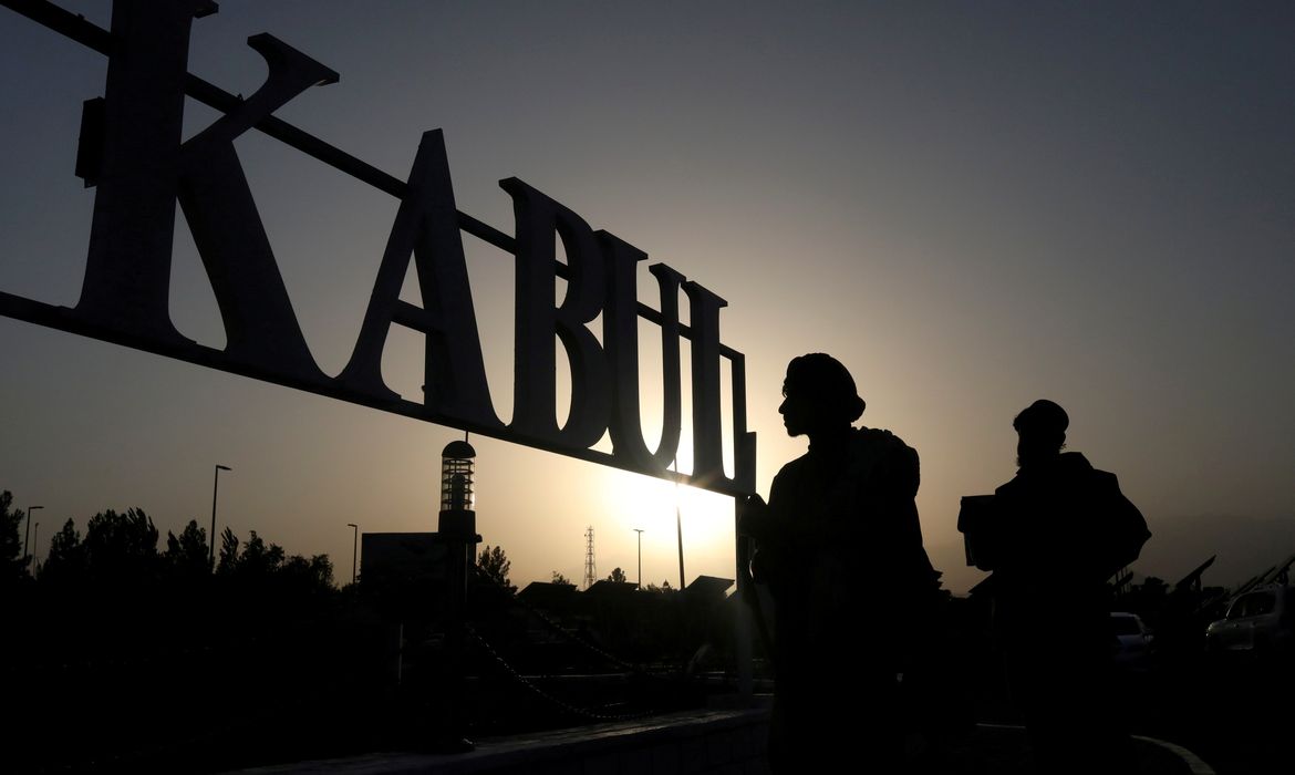 FILE PHOTO: Taliban soldiers stand in front of a sign at the international airport in Kabul
