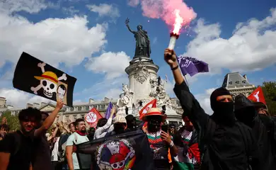 A masked protester holds a red flare during a demonstration at the Place de la Republique during a day of protests in Paris as part of a grassroots protest movement called 