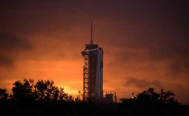 The sun sets behind a SpaceX Falcon 9 rocket with the company's Crew Dragon spacecraft onboard