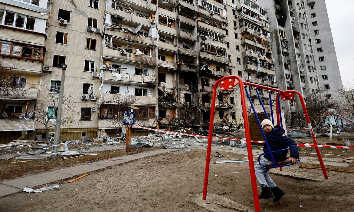 Criança em balanço em frente a prédio residencial danificado em Kiev após Rússia lançar ataque maciço à capital ucraniana