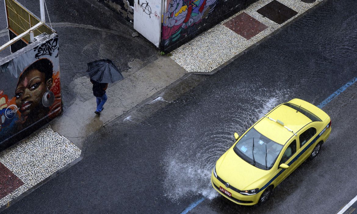 Rio de Janeiro - Pedestre caminha entre alagamentos na Rua da Relação, na Lapa, região central, durante temporal com forte chuva e vento  (Fernando Frazão/Agência Brasil)