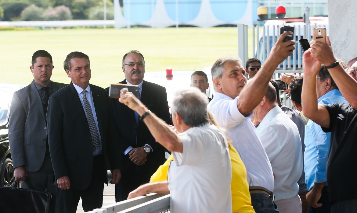 O Presidente Jair Bolsonaro cumprimenta populares ao sair do Palácio da Alvorada.