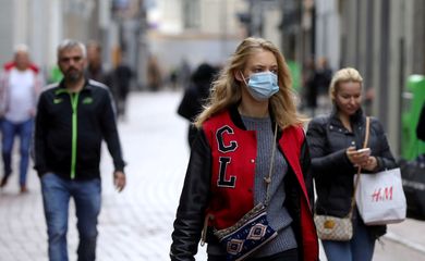 Pessoas com e sem máscara de proteção caminham em rua de Amsterdã