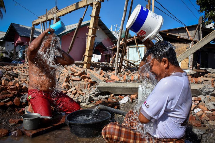 Homens tomam banho na região de Lombok, uma das mais afetadas pelo terremoto na Indonésia