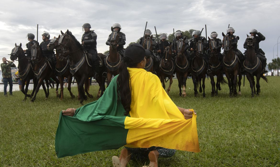 Brasilia 07/02/2023 - Manifestantes invadem predios publicos na praca dos Tres Poderes, na foto uma manifestante se ajoelha na frente da cavalaria montada da policia militar proximo predio do Tribunal Superior Federal (STF)