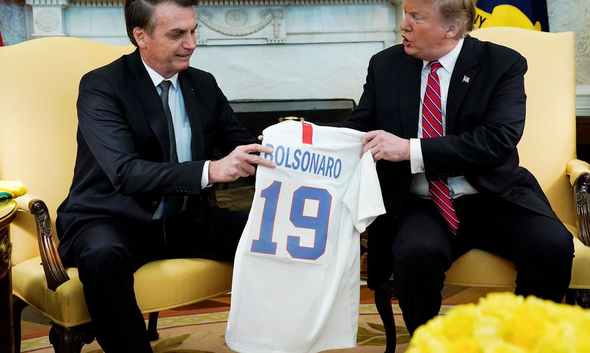 O presidente dos EUA, Donald Trump, dá ao presidente do Brasil, Jair Bolsonaro, uma camisa da seleção de futebol dos EUA durante uma reunião no Salão Oval da Casa Branca , em Washington (EUA). 