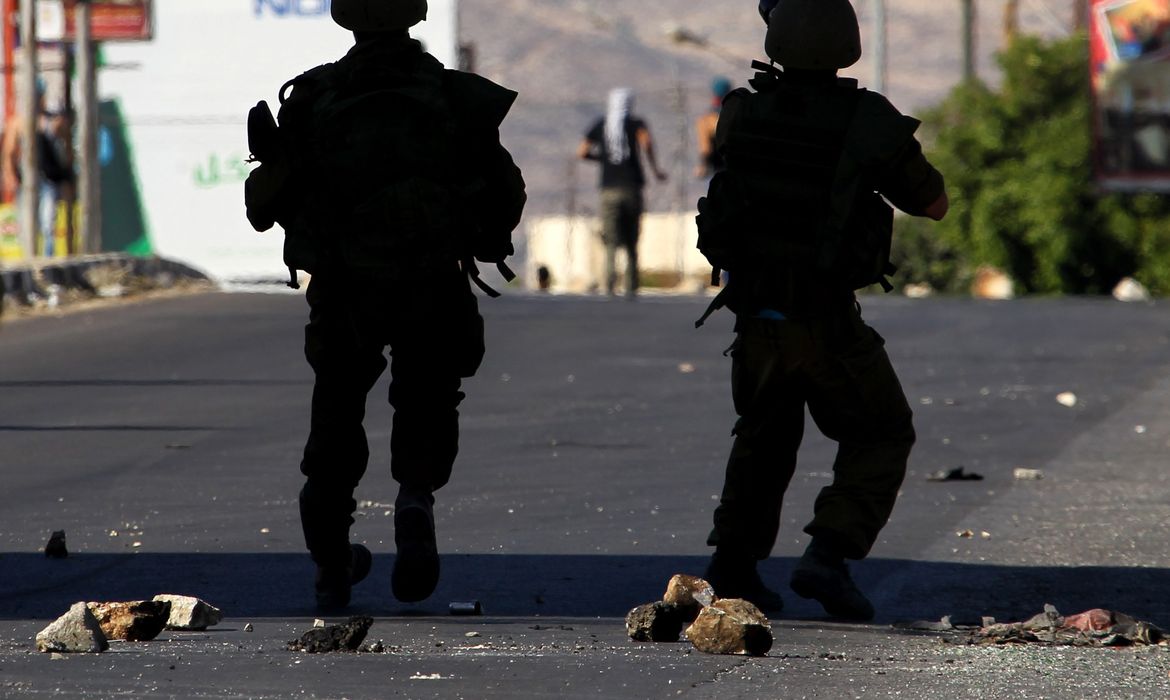 Soldados israelenses enfrentam manifestantes palestinos em protesto contra os ataques na Faixa de Gaza (Direitos Reservados/Alaa Badarneh/Agência Lusa) 