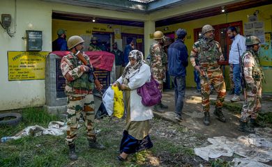 A woman leaves a polling station past Indian security force personnel standing guard during the fourth phase of India's general election on the outskirts of Srinagar May 13, 2024. REUTERS/Sanna Irshad Mattoo