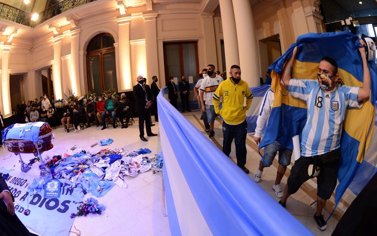 Divulgação/Presidência da Argentina People pass by the coffin holding the body of soccer legend Diego Maradona during his wake at the presidential palace Casa Rosada, in Buenos Aires