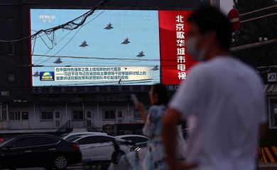 Telão exibe imagens de aviões do Exército de Libertação Popular chinês durante programa jornalístico em cruzamento de Pequim