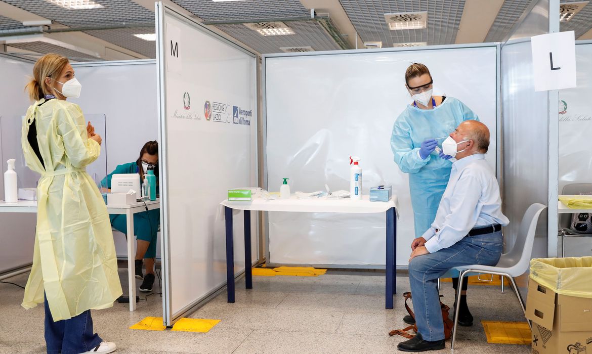 Profissional de saúde colhe amostra para exame de Covid-19 de homem no aeroporto de Fiumicino, em Roma