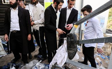 Ultra Orthodox Jews stand next to left over belongings on Mount Meron