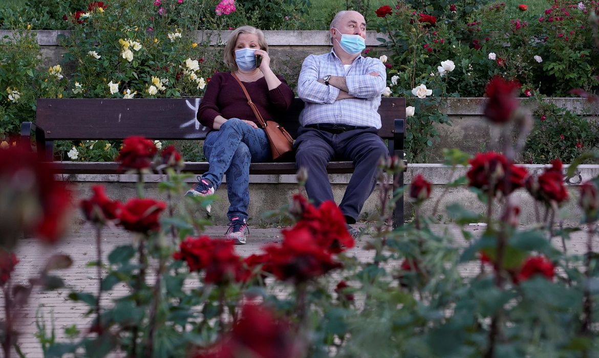 Pessoas que usam máscaras protetoras sentam-se em um parque, enquanto alguns parques da cidade reabrem em meio ao relaxamento das restrições implementadas para conter a propagação da doença por coronavírus (COVID-19), em Madri, Espanha
