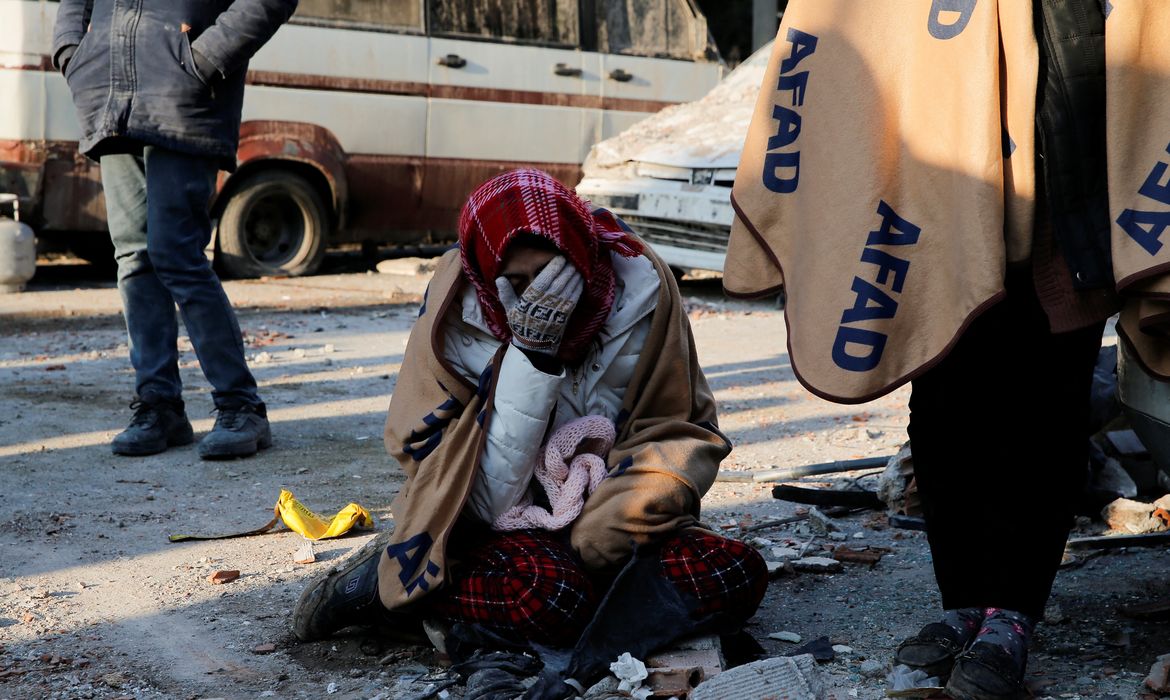 Mulher chora perto de local onde prédio desmoronou por causa de terremoto na Turquia