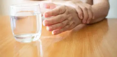 Pessoa com tremores tenta pegar um copo