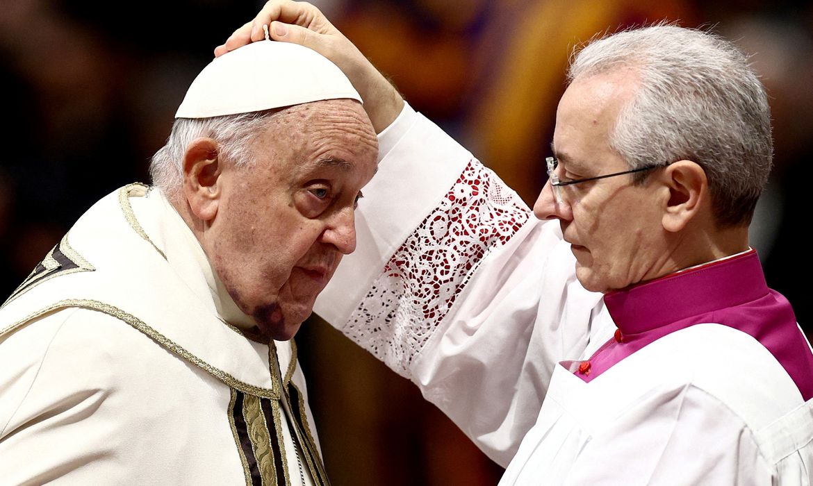 Vaticano- 07/12-2024 O Papa Francisco coloca a tradicional bireta vermelha, um chapéu de quatro pontas, na cabeça do novo cardeal durante uma cerimônia de consistório para elevar os prelados católicos romanos ao posto de cardeal, na Basílica de São Pedro, no Vaticano, em 7 de dezembro. 2024.REUTERS/Guglielmo Mangiapane/ Proibido reprodução