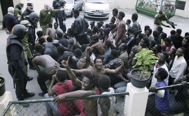 Dezenas de imigrantes subsaarianos celebram após ter conseguido pular a cerca fronteiriça da Espanha em Ceuta, norte da África, no dia 17 de fevereiro último