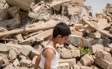 Menino passa em frente a casas destruídas no bairro de Al-Resala, na região oeste de Mossul, no Iraque