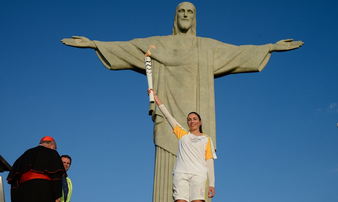 Rio de Janeiro - A ex-jogadora de vôlei Isabel Salgado segura a tocha olímpica em frente ao Cristo Redentor, uma das sete maravilhas do mundo moderno. O cardeal dom Orani Tempesta acendeu a chama olímpica  ( Tânia Rêgo/Agência Brasil)