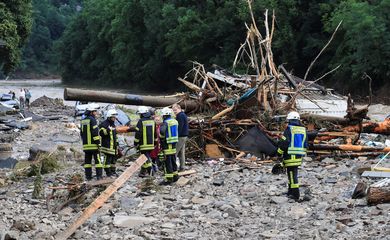 Bombeiros conversam com pessoas perto de escombros deixados pelas enchentes em Schuld, na Alemanha