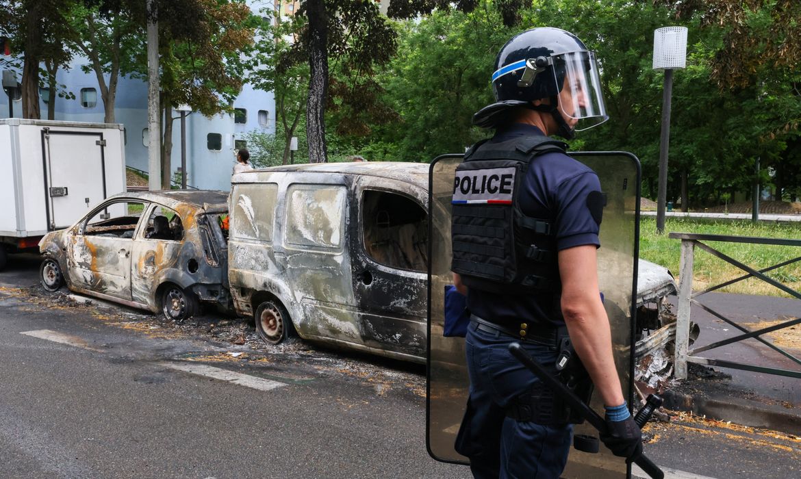 Um policial francês faz guarda ao lado de veículos queimados durante uma noite de confrontos entre manifestantes e policiais, após a morte de um adolescente de 17 anos morto por um policial francês durante uma parada de trânsito, em Nanterre, subúrbio de Paris, França, em 1º de julho de 2023. REUTERS/Yves Herman