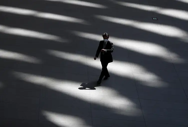 REUTERS/Issei Kato/Direitos Reservados A man wearing a protective face mask, following an outbreak of the coronavirus disease, walks past inside an almost empty convention complex in Tokyo, Japan