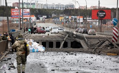 Pessoas fugindo da invasão russa à Ucrânia cruzam ponte destruída na região de Kiev