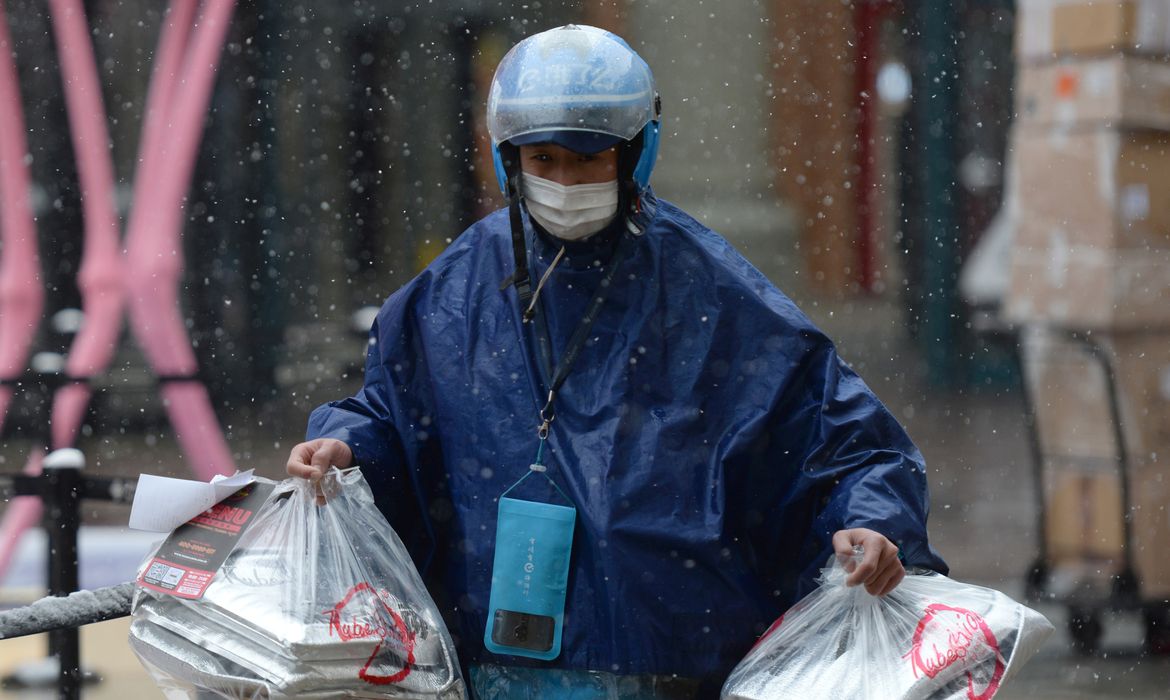 Ele.me deliveryman wearing a face mask delivers food amid snowfall on Valentine's Day in Beijing