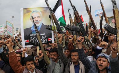 Protesters, mainly Houthi supporters, hold firearms next to a poster of assassinated Hamas chief Ismail Haniyeh, at the rally to show solidarity with Palestinians in the Gaza Strip, in Sanaa, Yemen, August 2, 2024. REUTERS/Khaled Abdullah