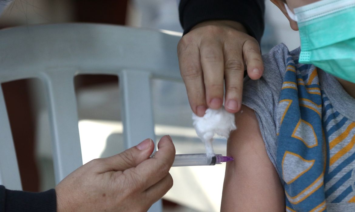 O menino Thomas Schneider, 4 anos, toma sua primeira dose de vacina contra a Covid-19 no Centro Municipal de Saúde Píndaro de Carvalho Rodrigues, na Gávea, zona sul da cidade. A cidade do Rio inicia hoje(15) a vacinação de crianças de 4 anos de