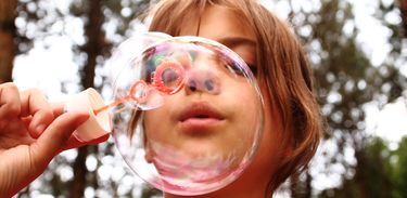 Criança soprando bolha de sabão