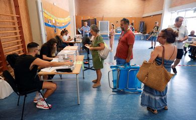 Monica Lopez and her husband carry beach chairs as they cast their votes during a general snap election at a polling station in Barcelona, Spain, July 23, 2023. REUTERS/Albert Gea
 