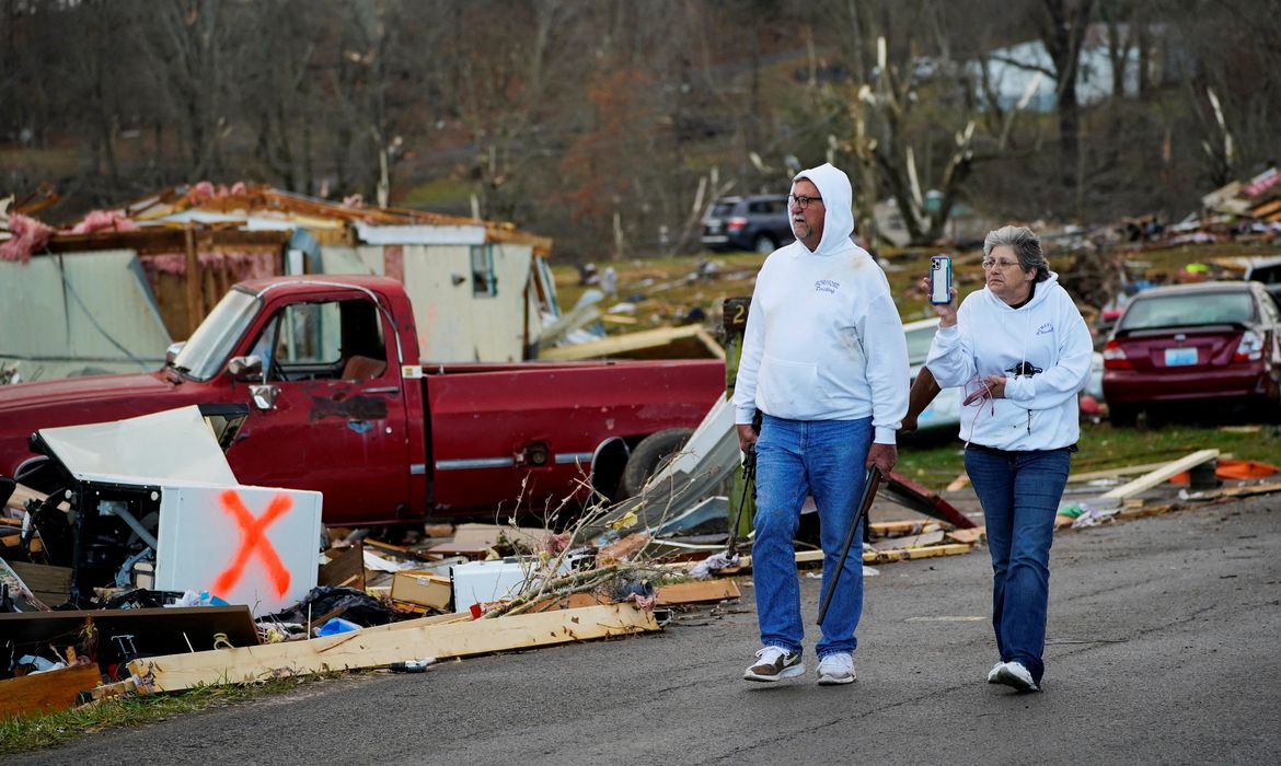 Casal caminha em meio a destroços em Earlington, Kentucky, após passagem de tufão