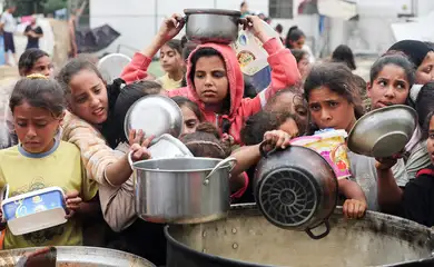 Palestinos aguardam para receber comida preparada por uma cozinha comunitária, em Nuseirat, Faixa de Gaza
08/04/2025
REUTERS/Ramadan Abed