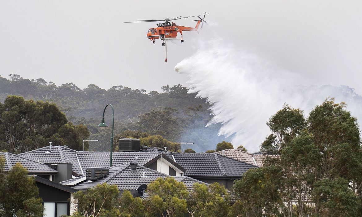A Sikorsky S-64 Skycrane helicopter drops water on a bushfire in scrub behind houses in Bundoora, Melbourne, Australia,December 30, 2019. AAP Image/Ellen Smith via REUTERS  ATTENTION EDITORS - THIS IMAGE WAS PROVIDED BY A THIRD PARTY. NO RESALES