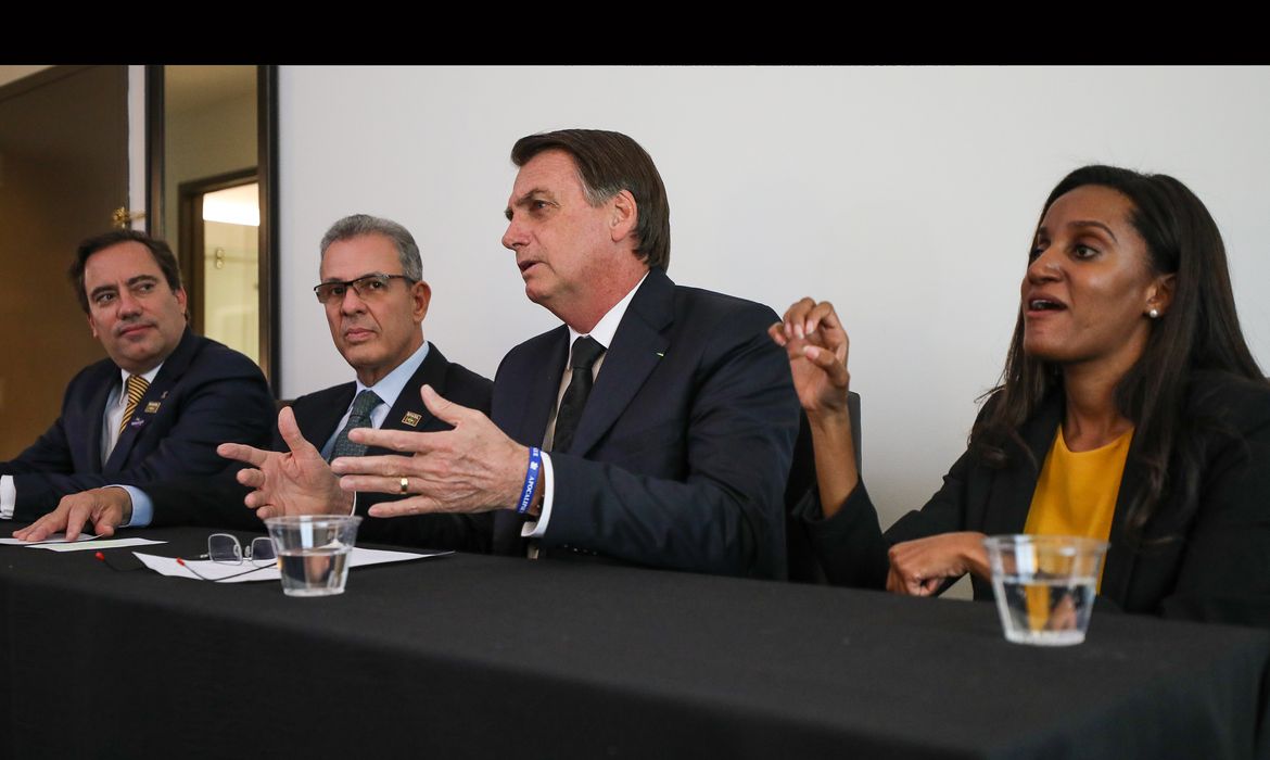 O presidente Jair Bolsonaro, em Dallas (EUA), faz transmissão ao vivo para as redes sociais. ao lado do presidente da Caixa, Pedro Guimarães, do ministro de Minas e Energia, Bento Albuquerque, e da intérprete de libras, Joyce Porto.