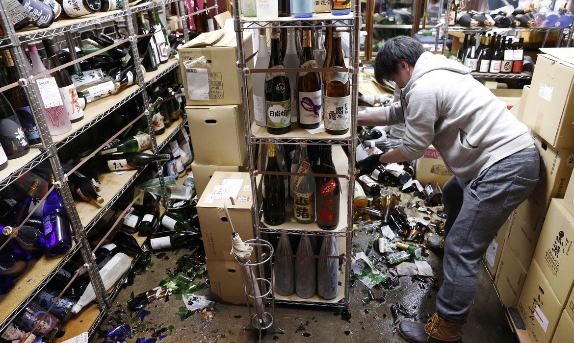 A worker cleans up broken bottles at a liquor shop after a strong quake in Fukushima
