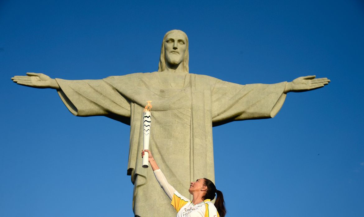 Rio de Janeiro - A ex-jogadora de vôlei Isabel Salgado segura a  tocha olímpica em frente ao Cristo Redentor, uma das sete maravilhas do mundo moderno. O cardeal dom Orani Tempesta acendeu a chama olímpica  ( Tânia Rêgo/Agência Brasil)